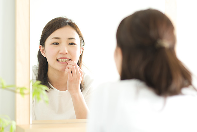 口元を鏡で確認する女性