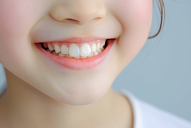 歯を見せて笑う少女の口元