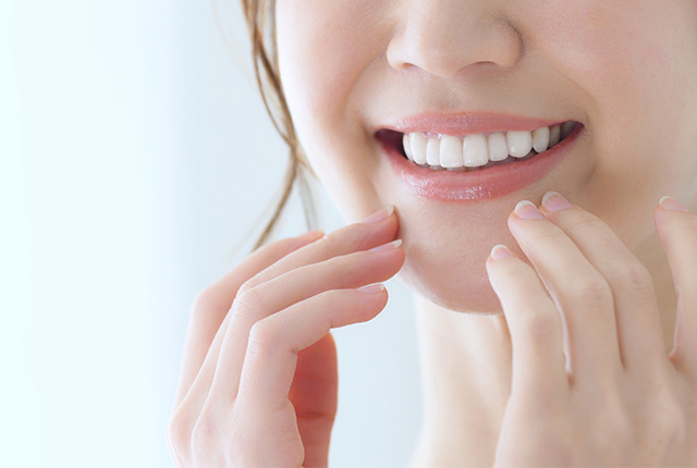 歯を見せて微笑み口元に手をそえる女性